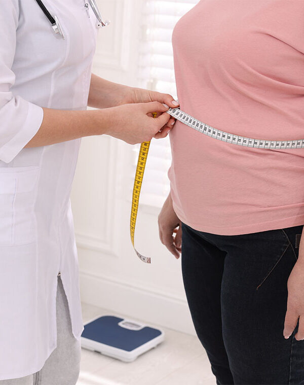 doctor measuring an overweight woman's waist
